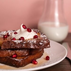 French toast topped with whipped cream and pomegranate seeds.