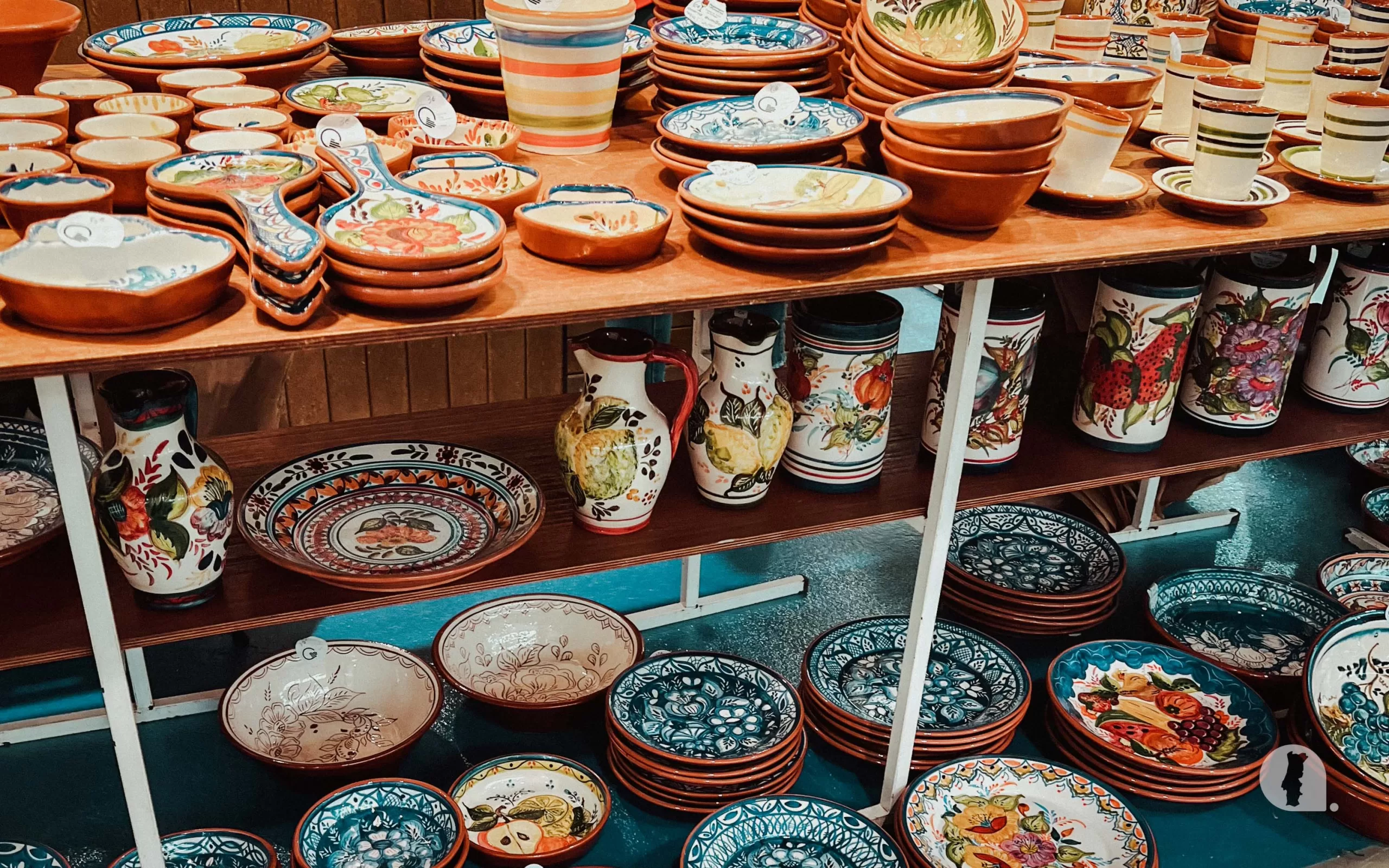 Various handcrafted and handpainted ceramic dishware displayed on shelves